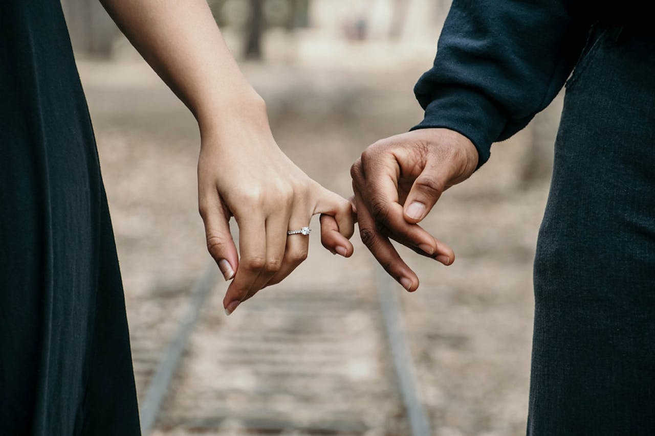 gallery-5 A romantic couple holding hands, symbolizing love and unity on a scenic railtrack.